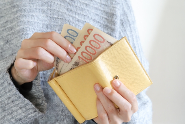 黄色の財布からお金を出す女性の手元
